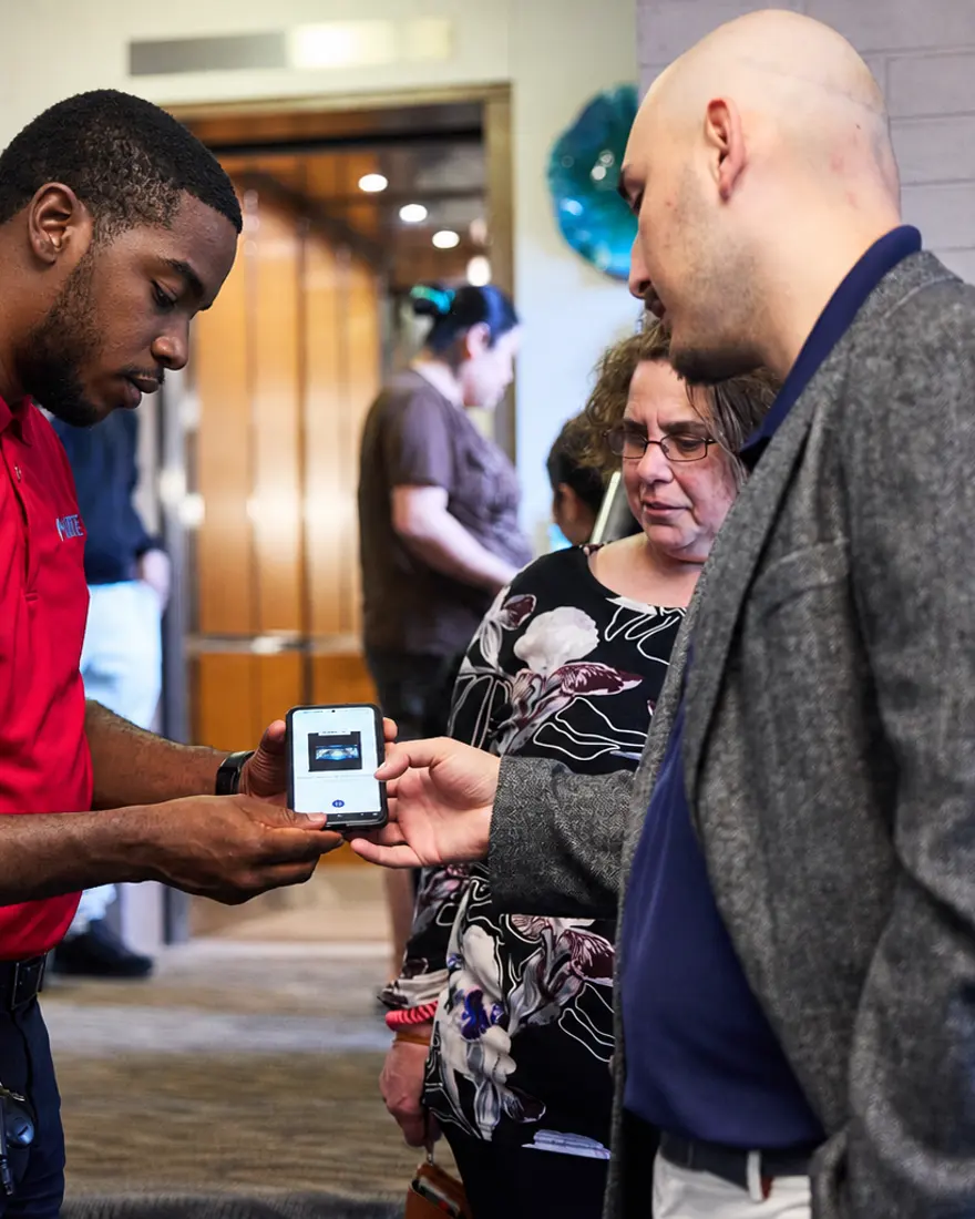 A team member walking residents through the app on a phone in a building lobby.