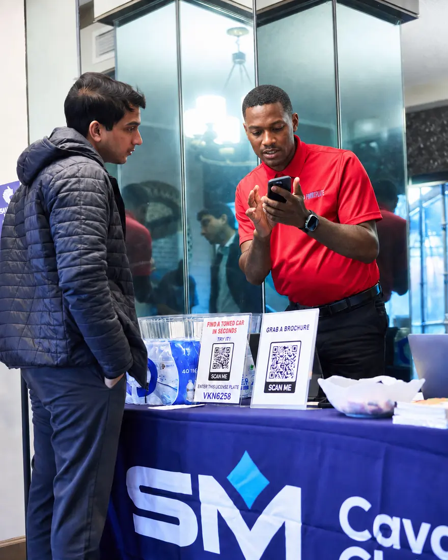 A team member helping a visitor register at a community event table.